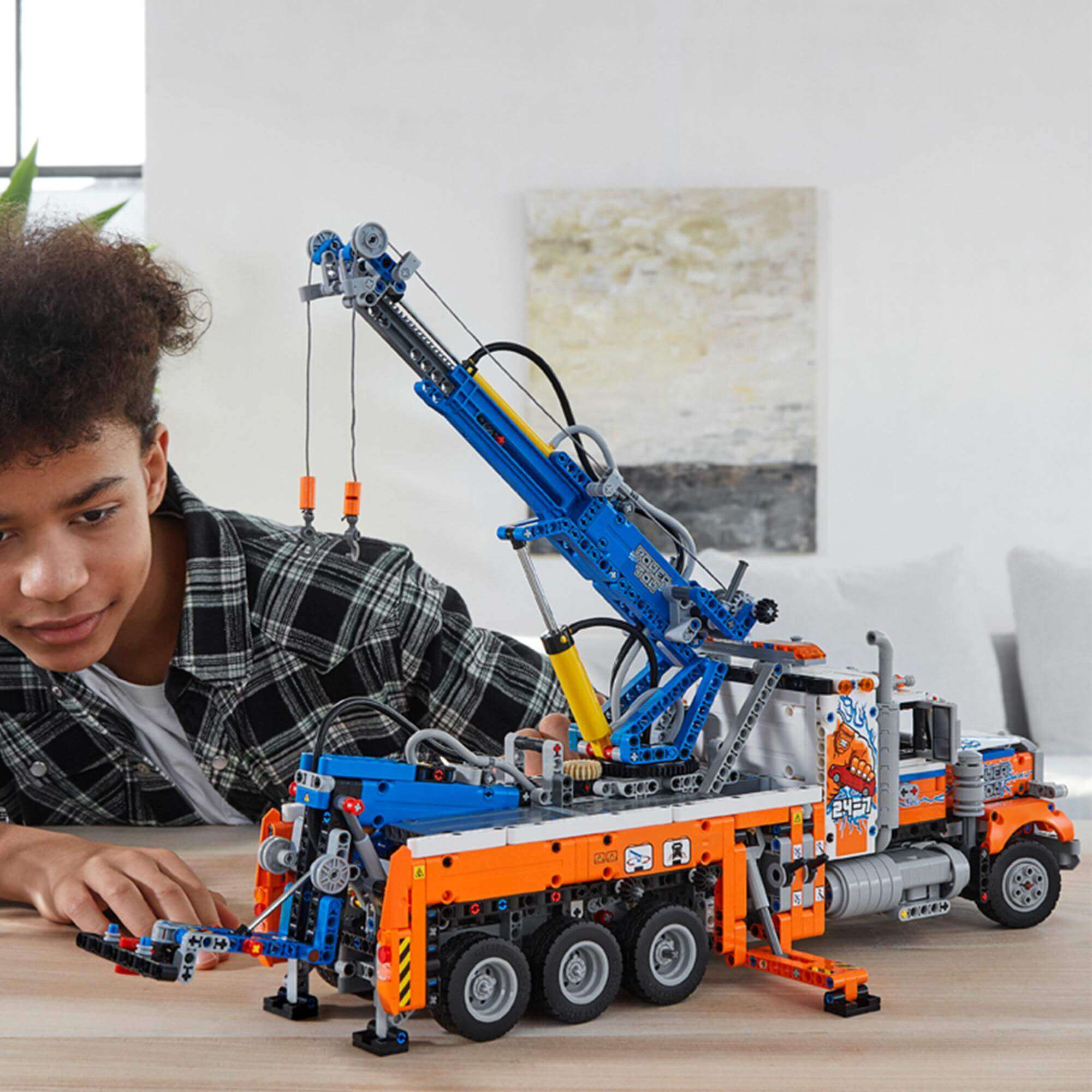 Child building the LEGO® Technic Heavy-Duty Tow Truck Toy 42128 with realistic crane features.