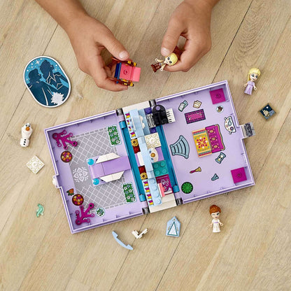 Child playing with LEGO Disney Frozen II Anna and Elsa's Storybook 43175 micro-world set with dolls and accessories.