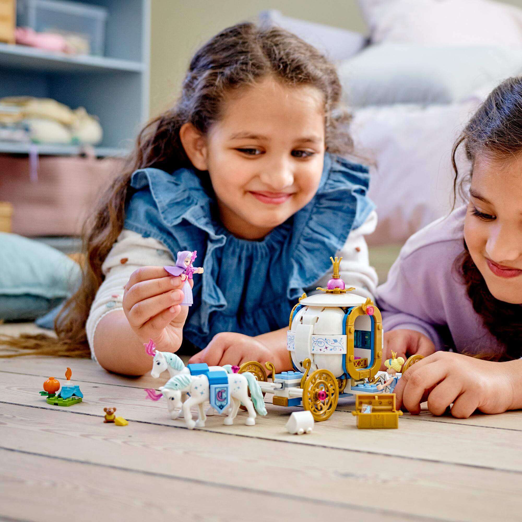 Two children playing with LEGO® Disney Cinderella’s Royal Carriage Toy 43192, featuring a gold carriage and horse figures.