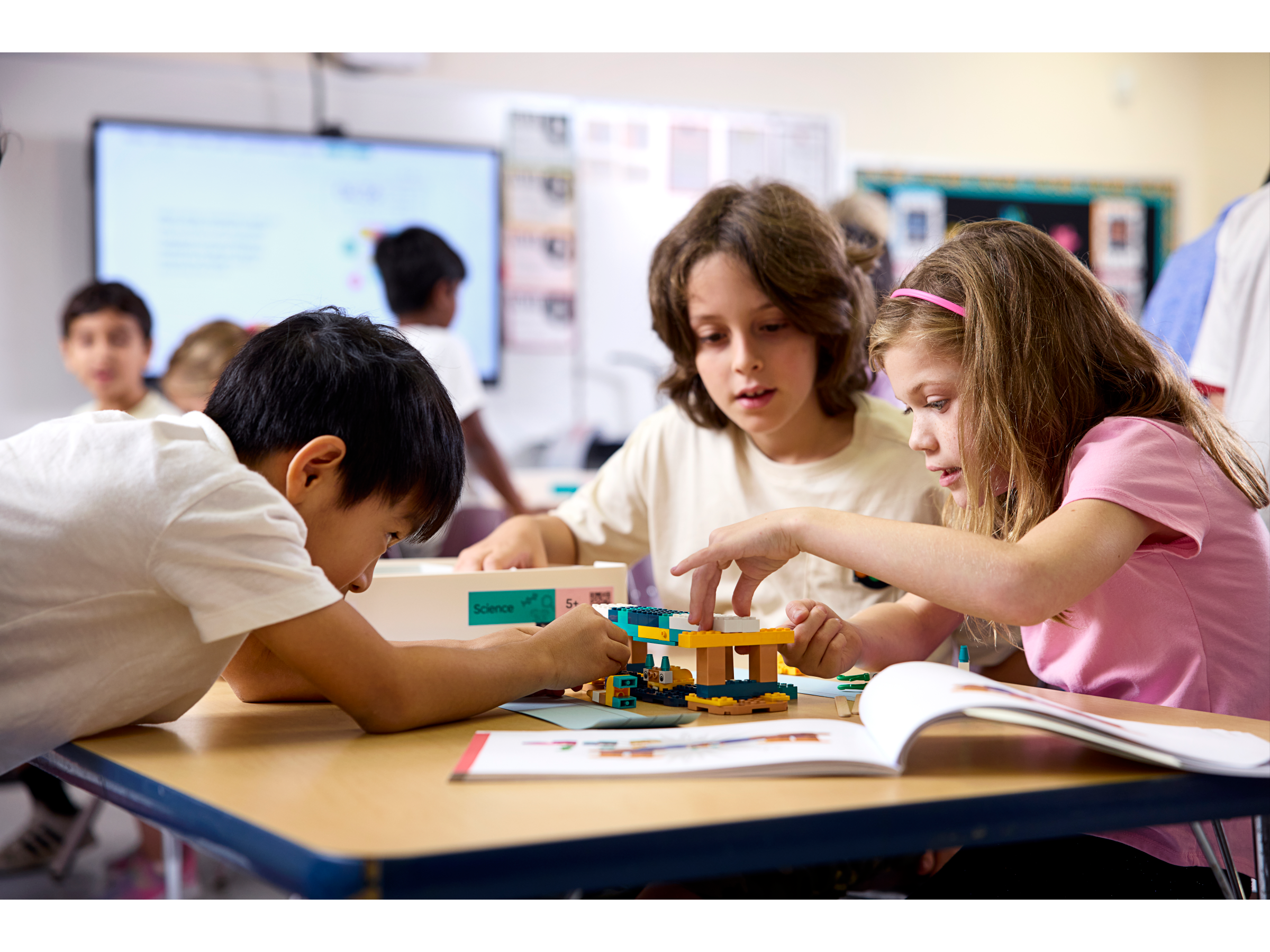 Children collaborating on a STEM project at a classroom table, building with colorful blocks and engaging in hands-on learning.