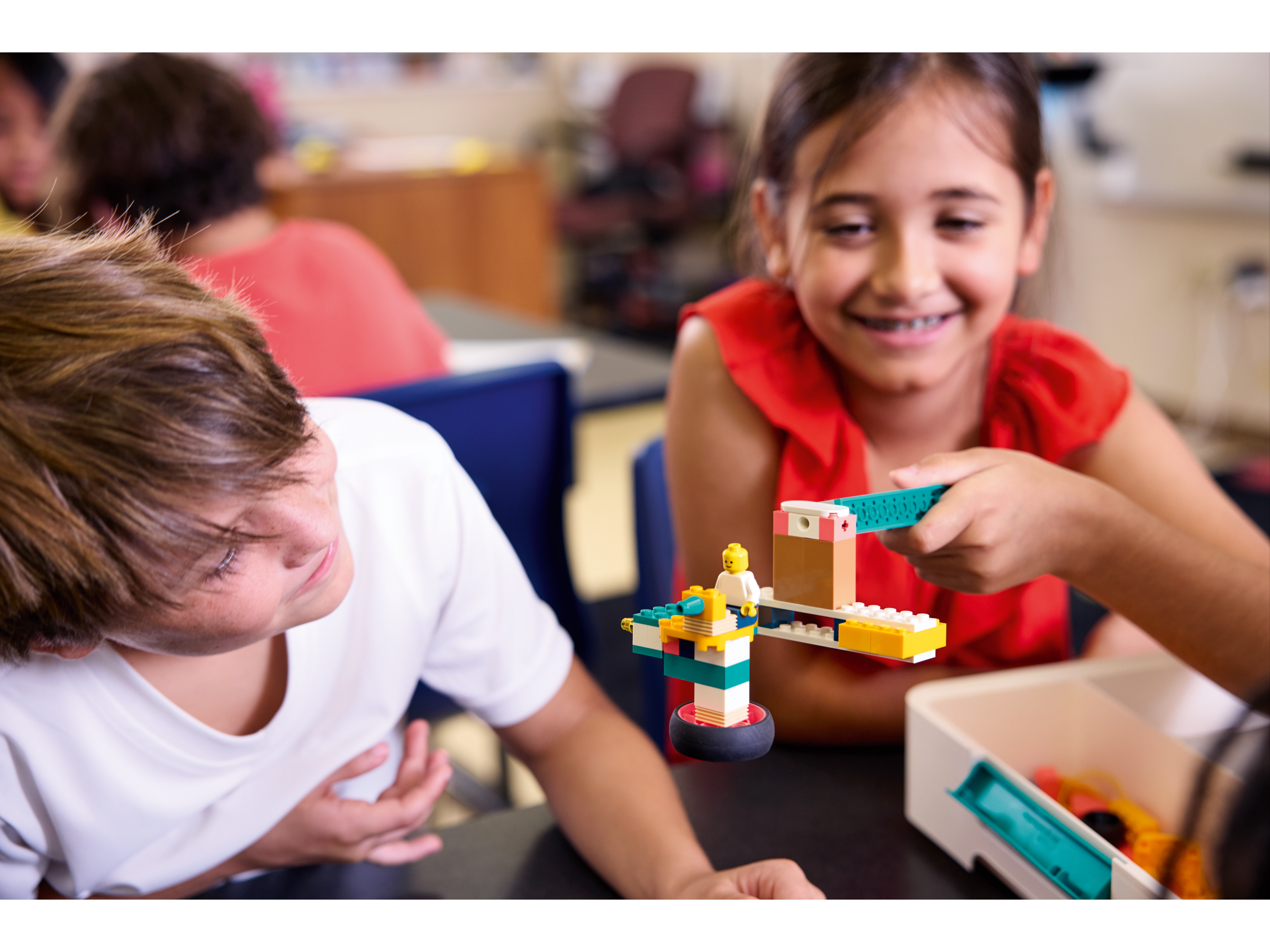 Children engaged in creative play with colorful LEGO bricks in a classroom setting.