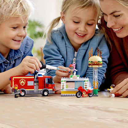 Kids playing with LEGO® City Burger Bar Fire Rescue Engine set 60214, featuring a fire truck, burger stand, and minifigures.