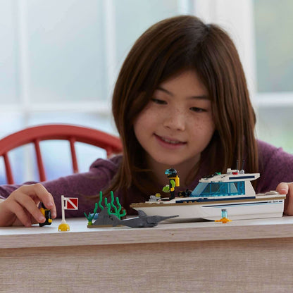 Child playing with LEGO® City Diving Yacht 60221 set featuring a boat and underwater scene.