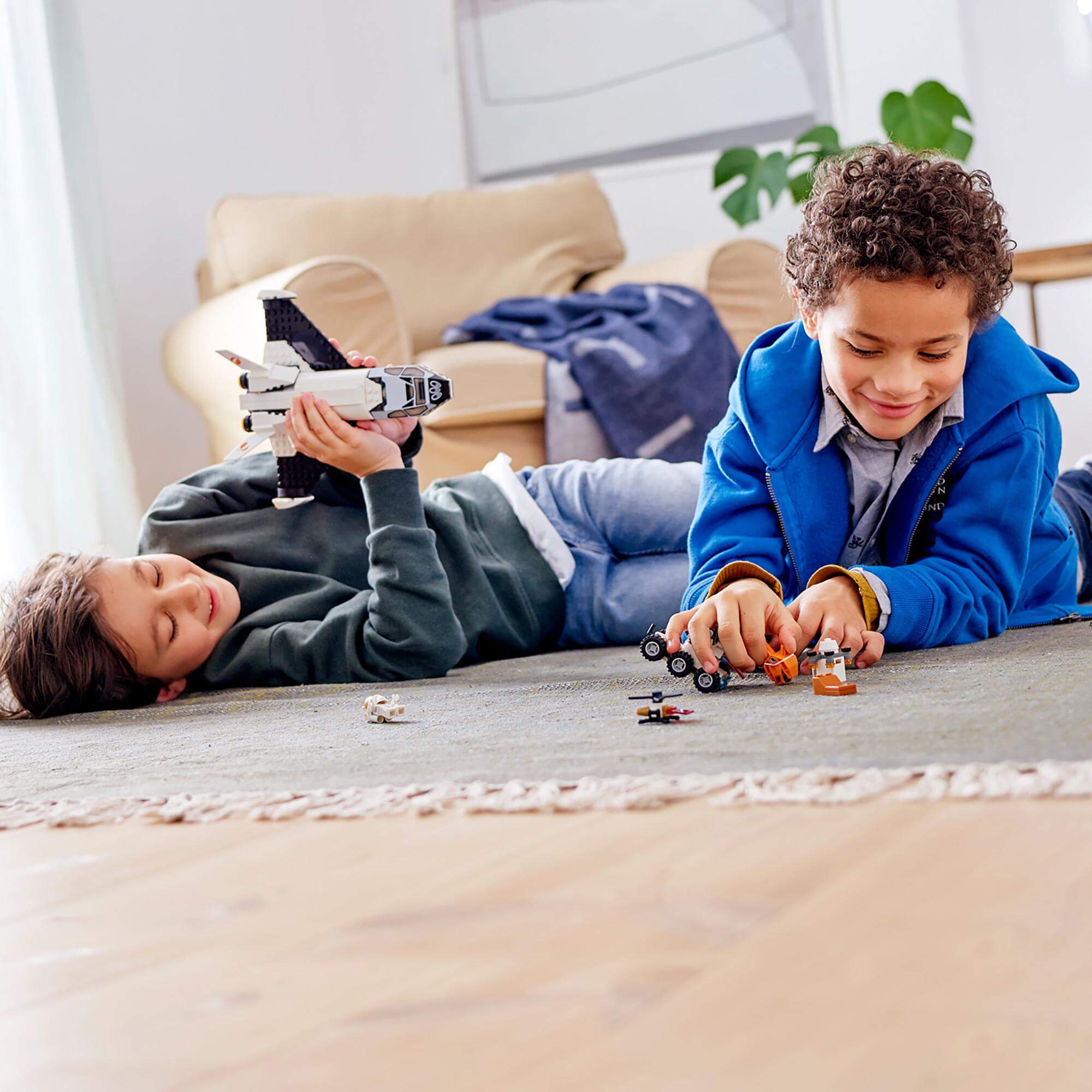 Two kids playing with LEGO® City Mars Research Shuttle and rover on the floor, engaging in imaginative space adventures.