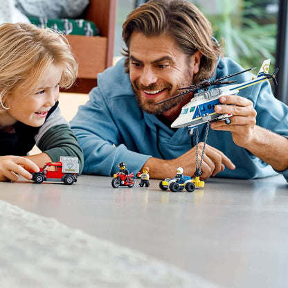 Father and son playing with LEGO® City Police Helicopter Chase Set 60243, featuring a toy helicopter and vehicles.