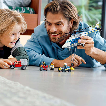 Father and son enjoying the LEGO® City Police Helicopter Chase Set 60243, playing with helicopter and vehicles.