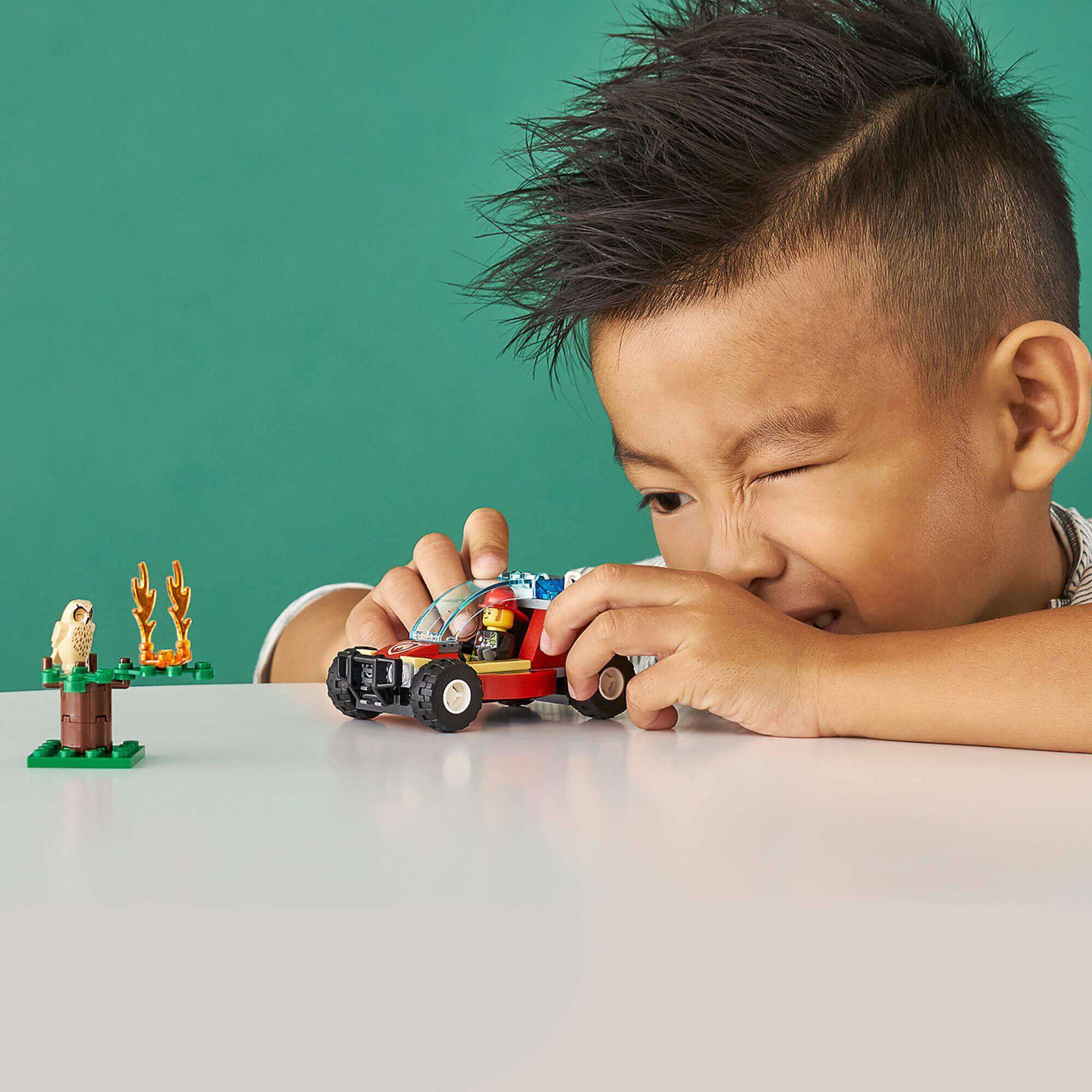 Child playing with LEGO® City Forest Fire Buggy Toy 60247, engaged in imaginative firefighting action.