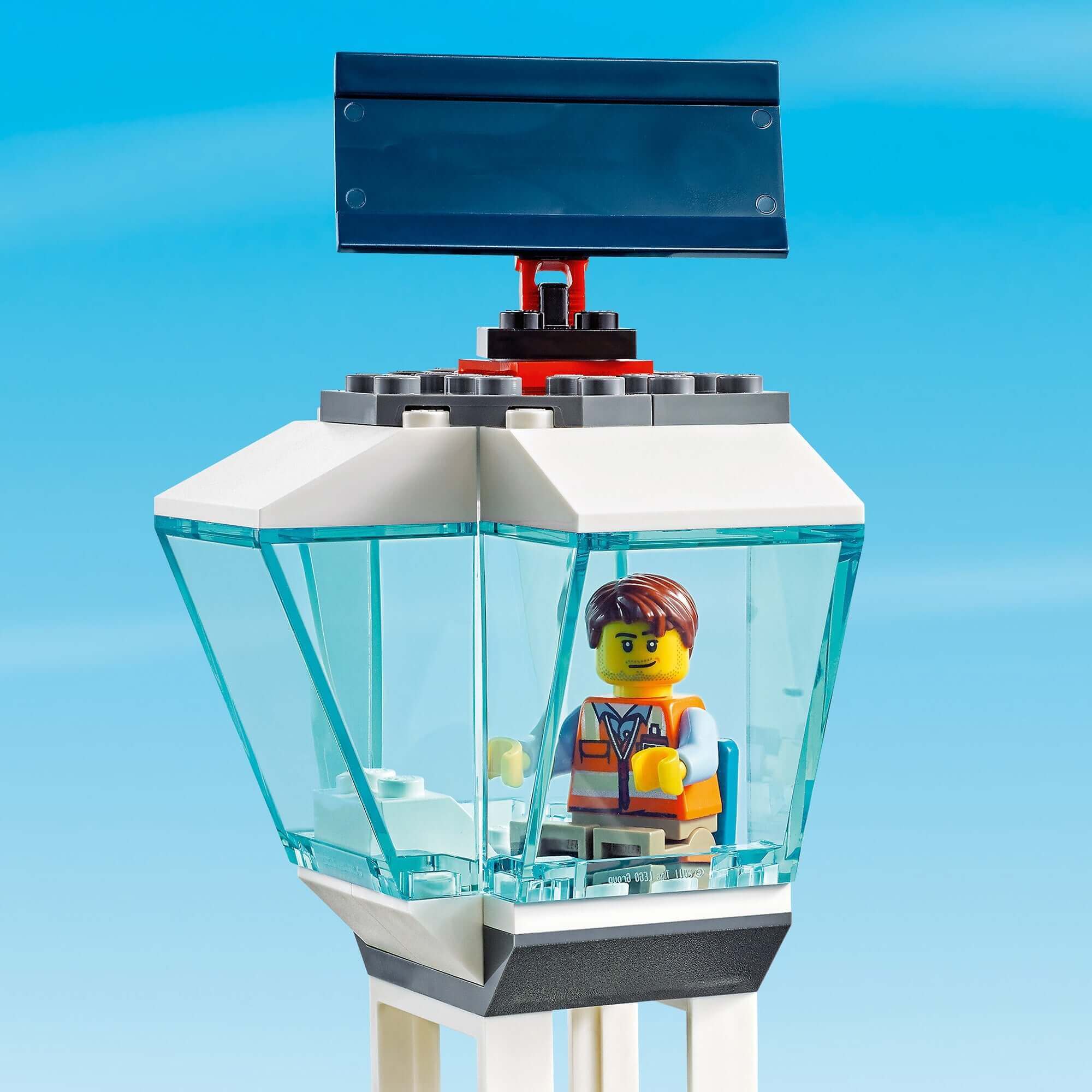 LEGO® City Airport control tower with a minifigure in the tower, set against a blue sky.