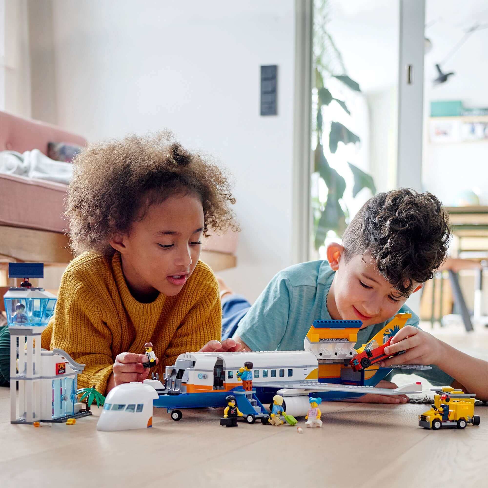 Children playing with LEGO® City Airport Passenger Airplane toy, featuring mini-figures and accessories for imaginative fun.