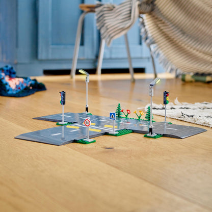 LEGO City Road Plates set featuring toy streetlights, traffic lights, and road signs on a wooden floor.