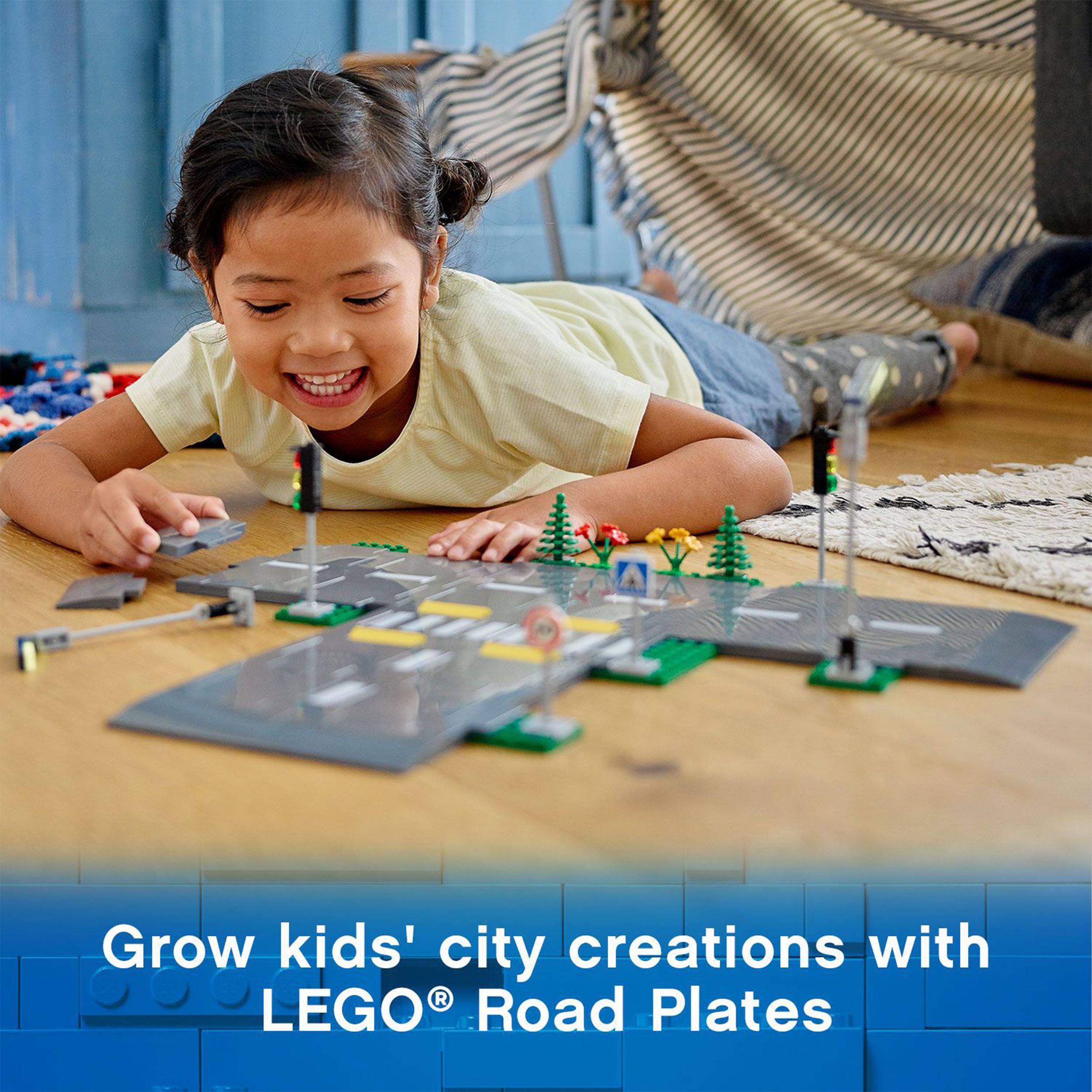 Child playing with LEGO® City Road Plates set, featuring streetlights and traffic signs for interactive city building.
