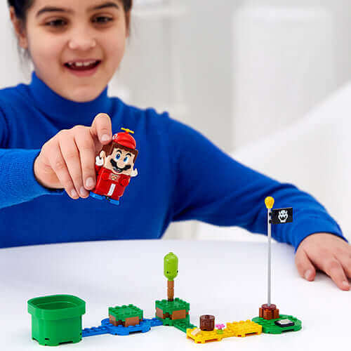 Child playing with LEGO® Super Mario™ figure and interactive blocks, creating a fun game scene.