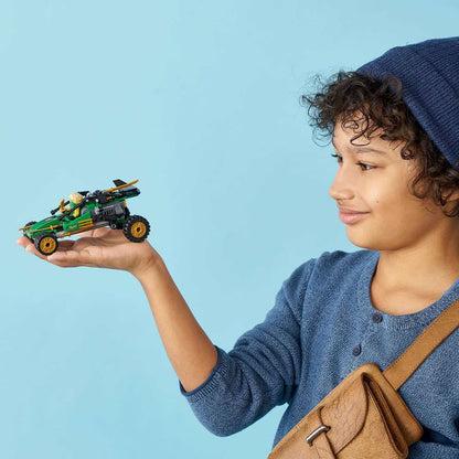 Child holding LEGO® NINJAGO Legacy Jungle Raider Set 71700, showcasing creativity and play in a vibrant setting.