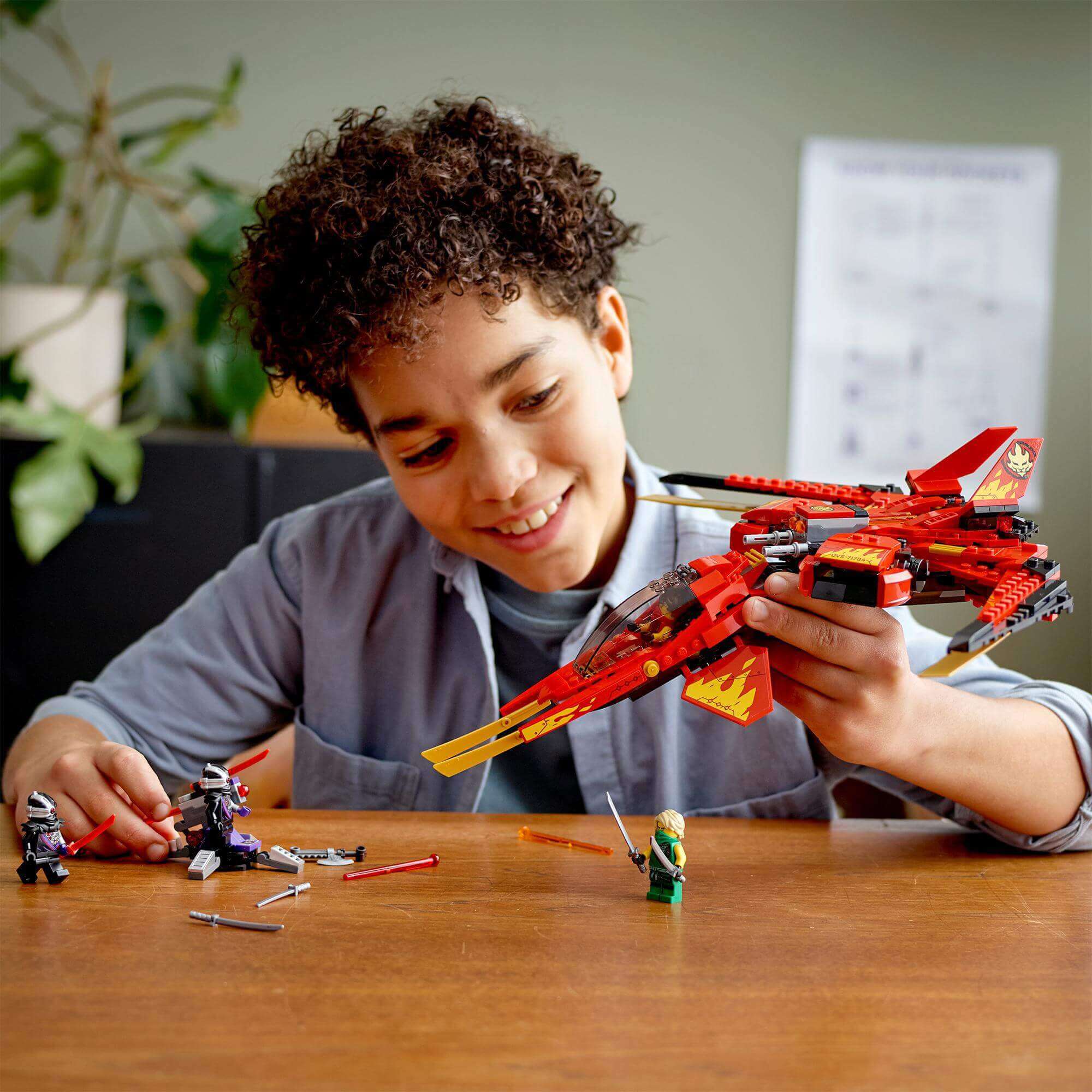 Child enjoying LEGO® NINJAGO Legacy Kai Fighter 71704 with figures, creating an action-packed scene in New NINJAGO City.