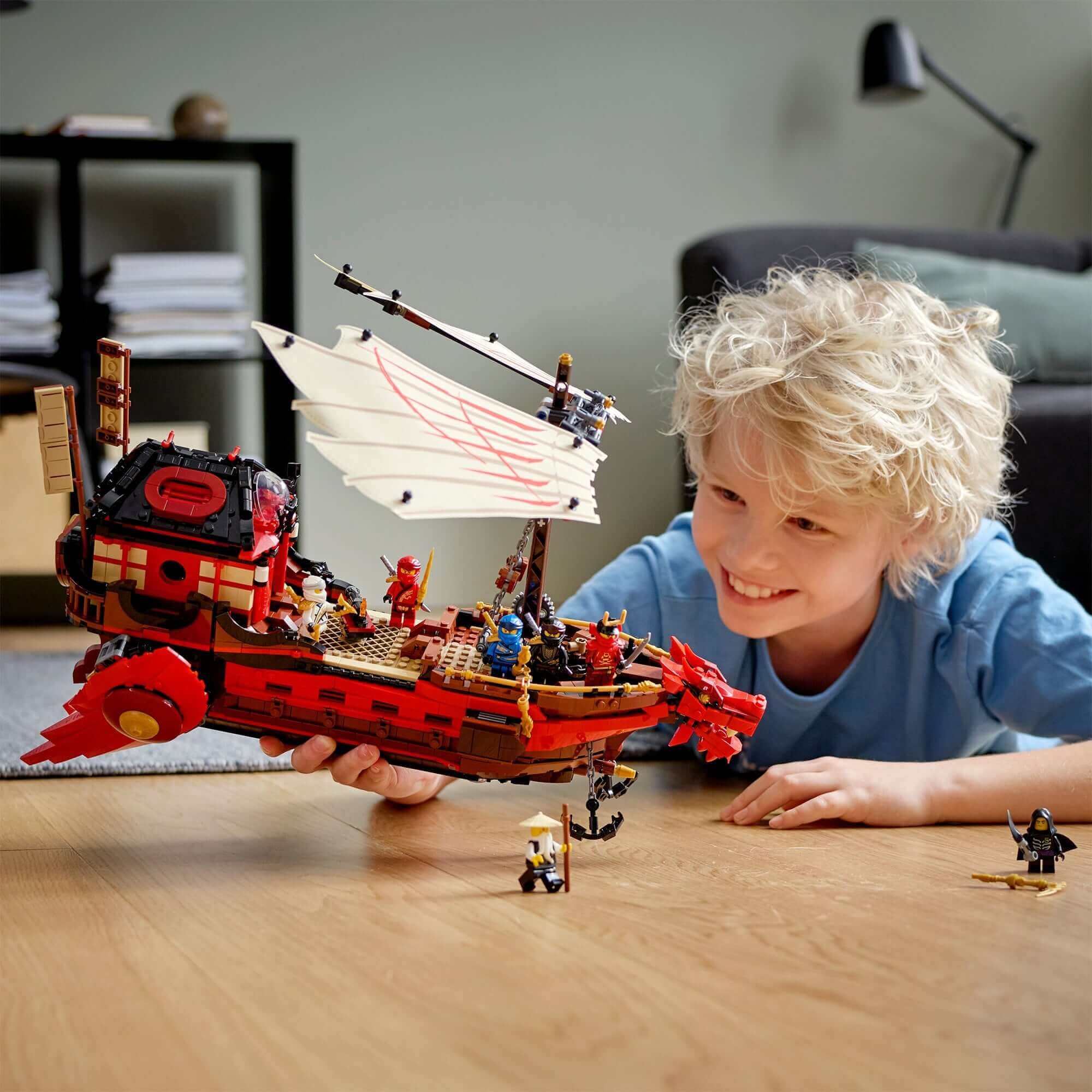 Child playing with LEGO® NINJAGO Destiny's Bounty ship set, featuring minifigures and exciting storytelling action.