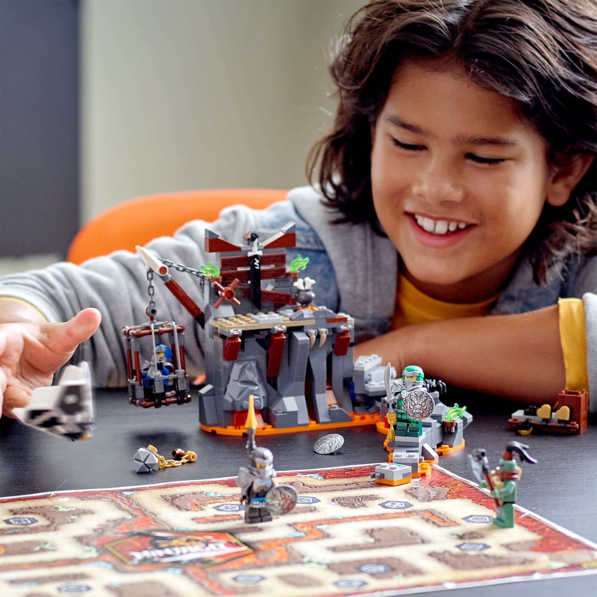 Child enjoying LEGO® NINJAGO Journey to the Skull Dungeons Set 71717 with vibrant playset and board game.