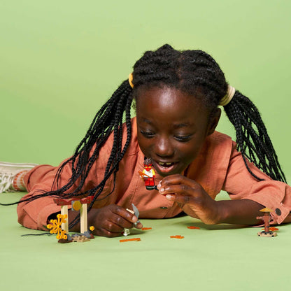 Child playing with LEGO® NINJAGO set, enjoying Kai vs. Skulkin battle on a green background.