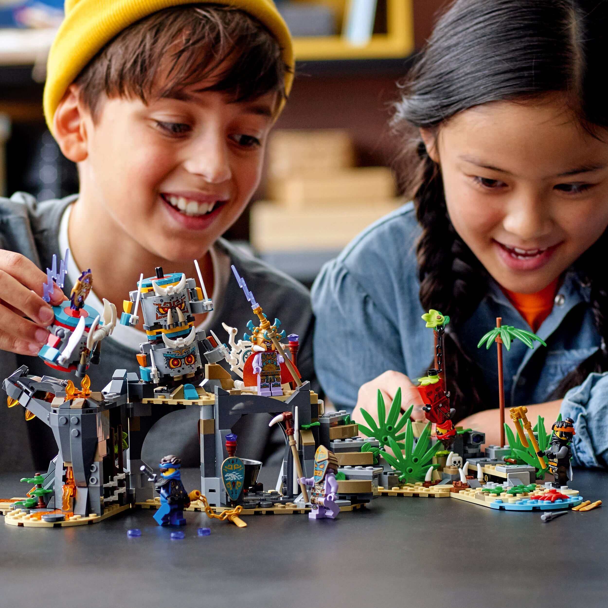 Kids playing with LEGO® NINJAGO The Keepers’ Village Building Set 71747, featuring traps and a prison.