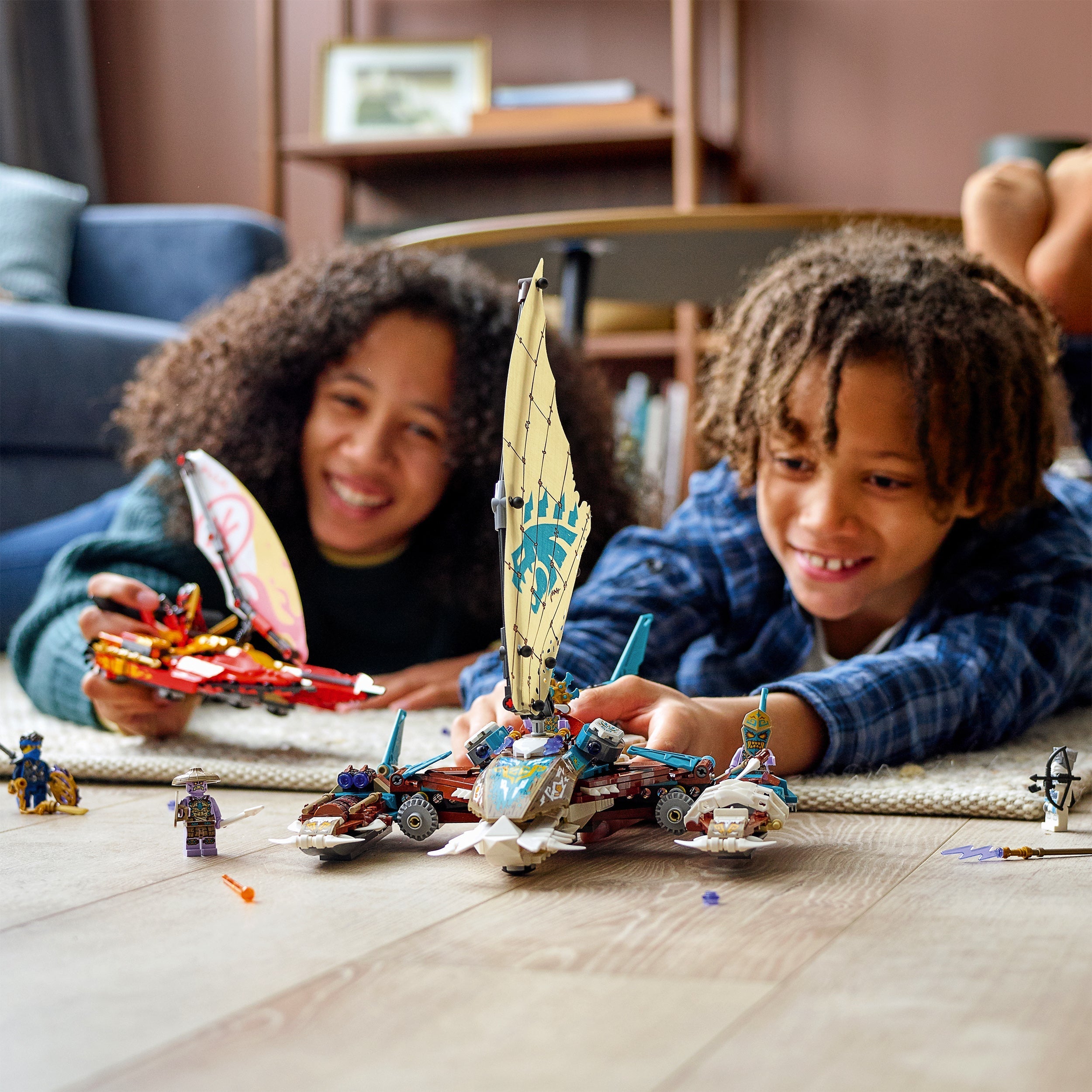 Kids playing with LEGO® NINJAGO Catamaran Sea Battle set 71748, featuring boats and minifigures.