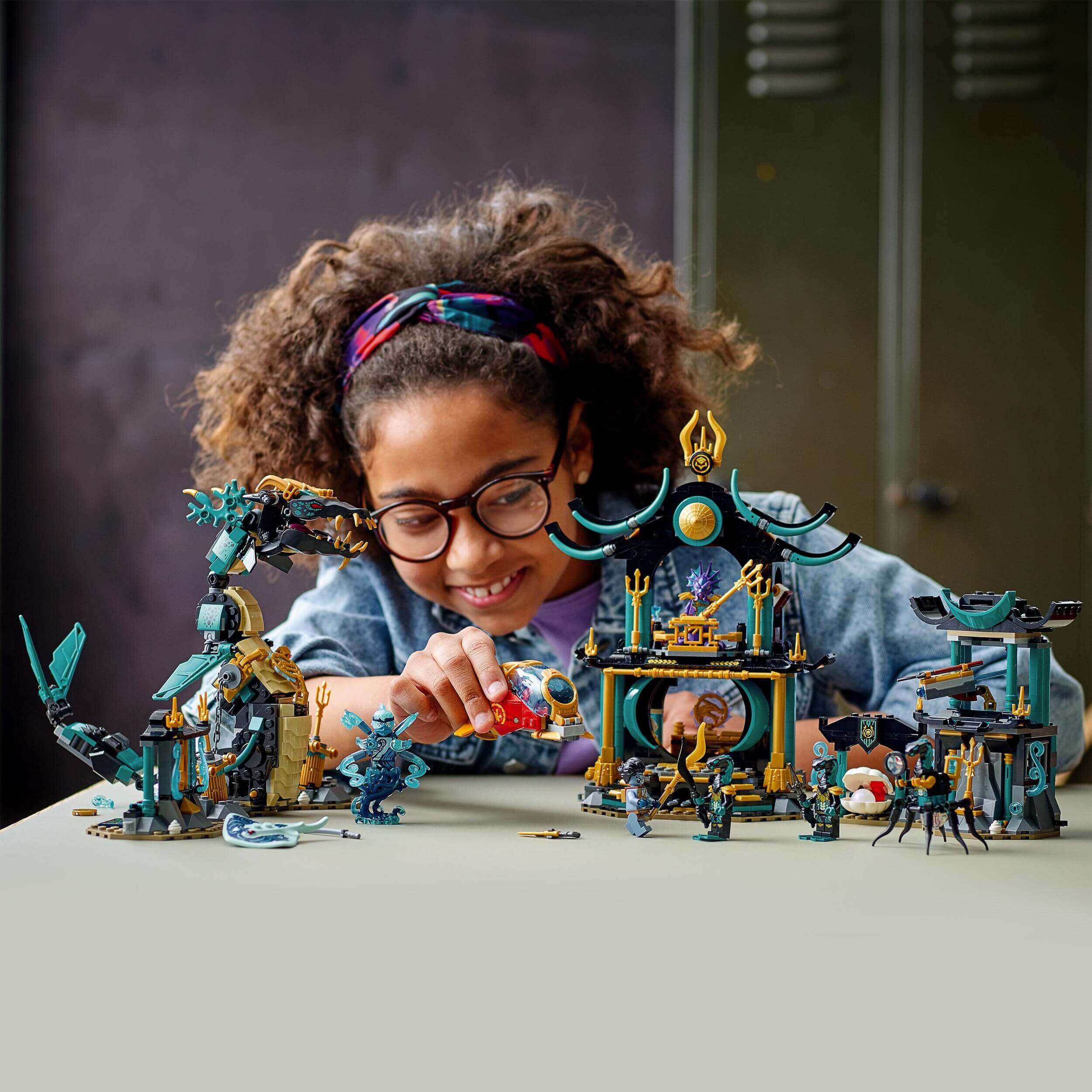 Child playing with LEGO® NINJAGO Temple of the Endless Sea Set 71755, featuring detailed underwater scenes and minifigures.