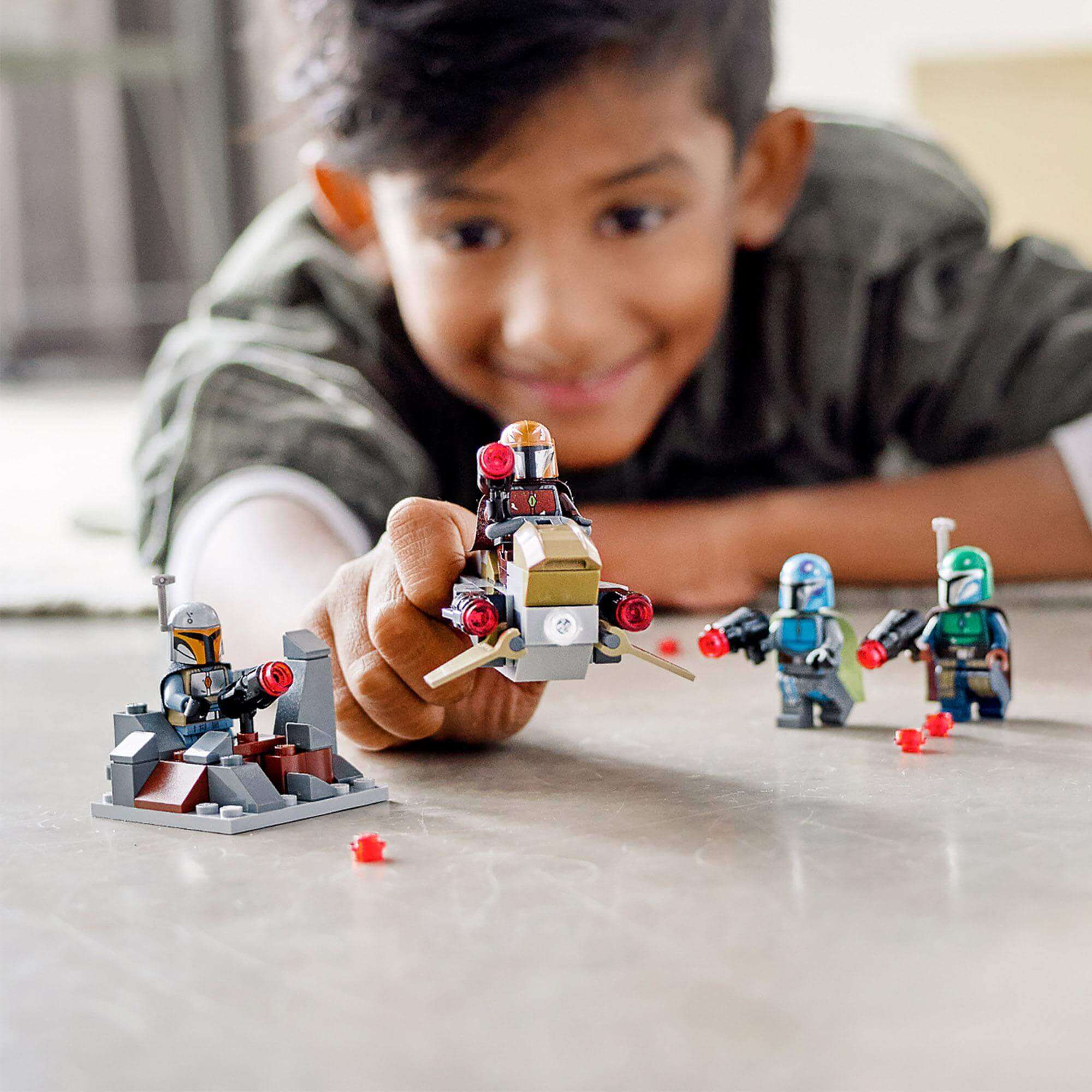 Child playing with LEGO® Star Wars Mandalorian Battle Pack Set 75267, featuring a speeder and buildable figures.