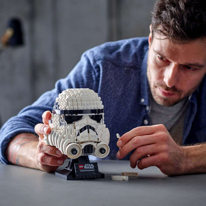 Person assembling the LEGO® Star Wars Stormtrooper Helmet Model Set 75276 on a table.