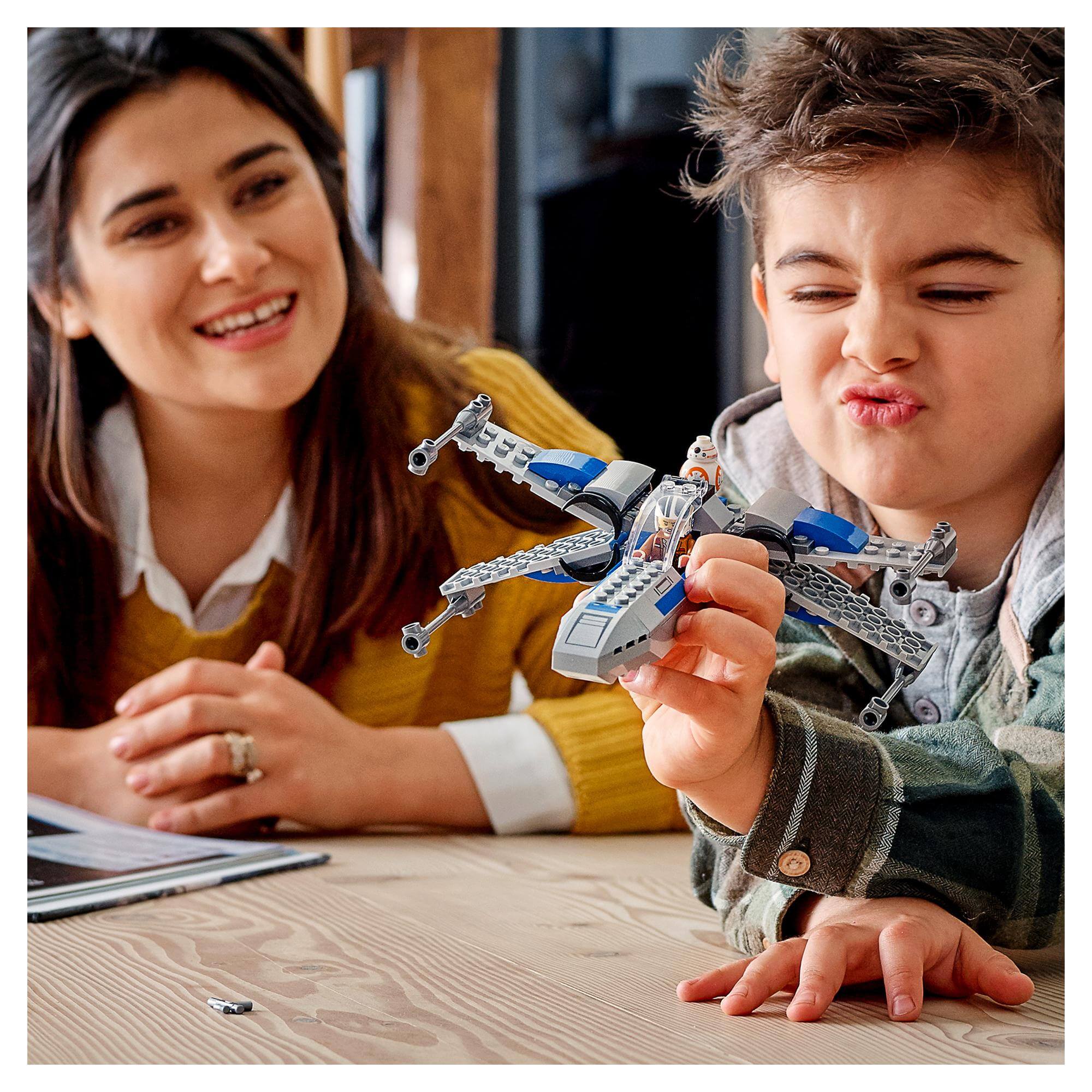 Child plays with LEGO® Star Wars Resistance X-Wing set while mother watches, showcasing creativity and fun.