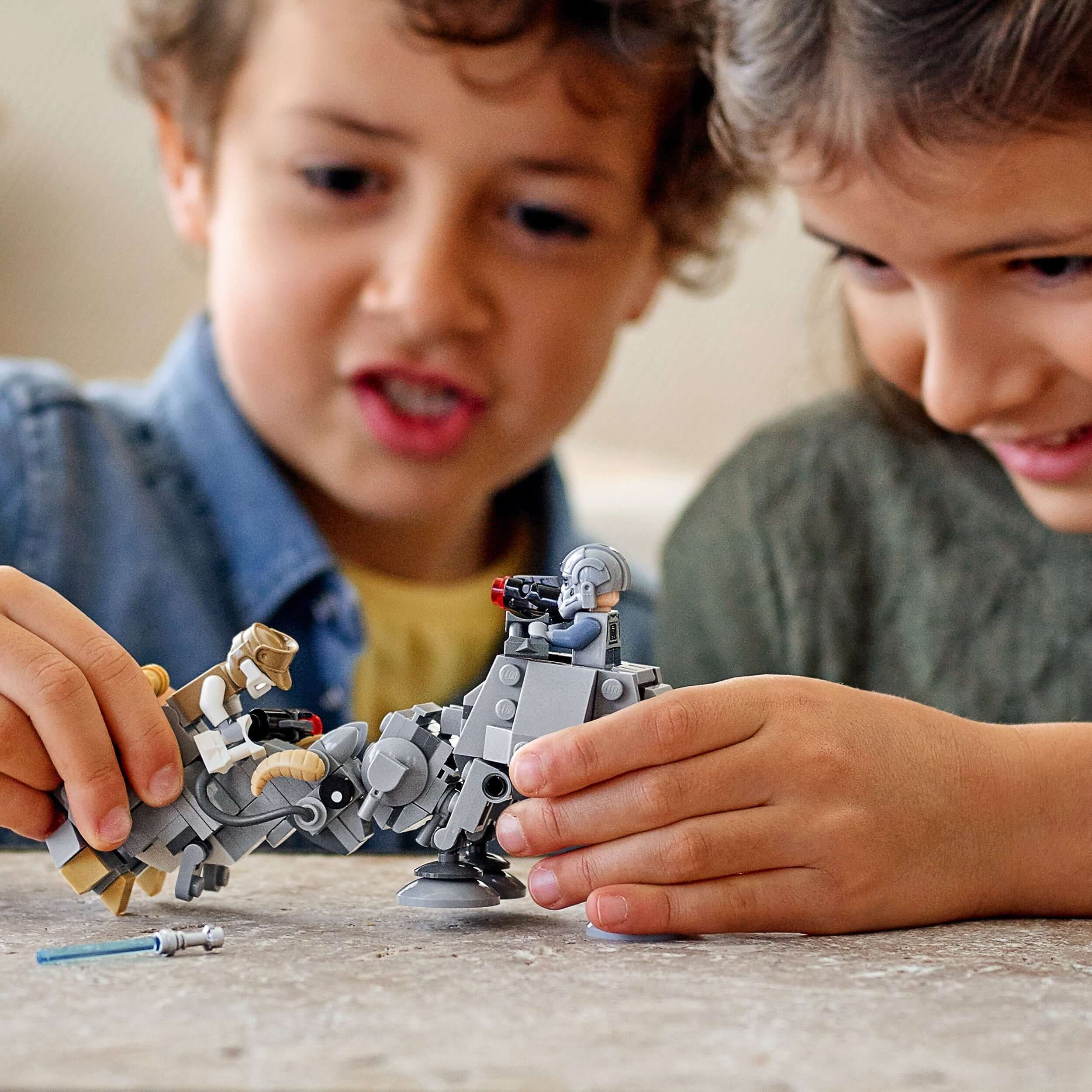 Kids playing with LEGO® Star Wars AT-AT and Tauntaun Microfighters, showcasing imaginative battle play.