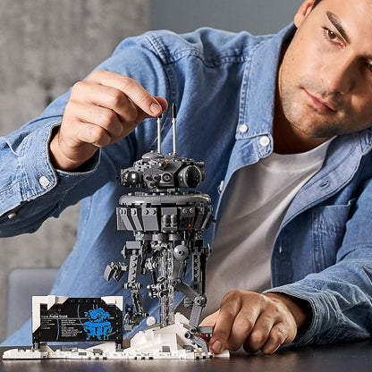 Adult assembling LEGO® Star Wars Imperial Probe Droid set 75306 in snowy Hoth scene, highlighting detailed model design.