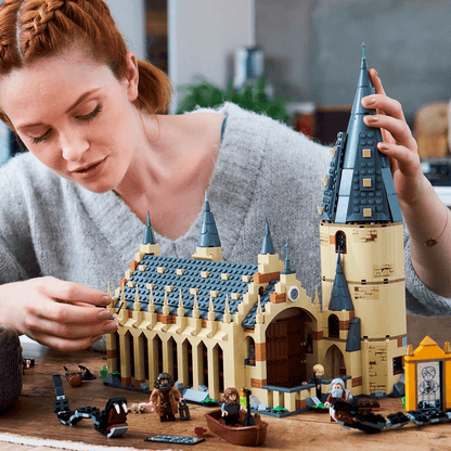 Woman building LEGO® Harry Potter Great Hall Castle Set 75954 with detailed architecture and minifigures.