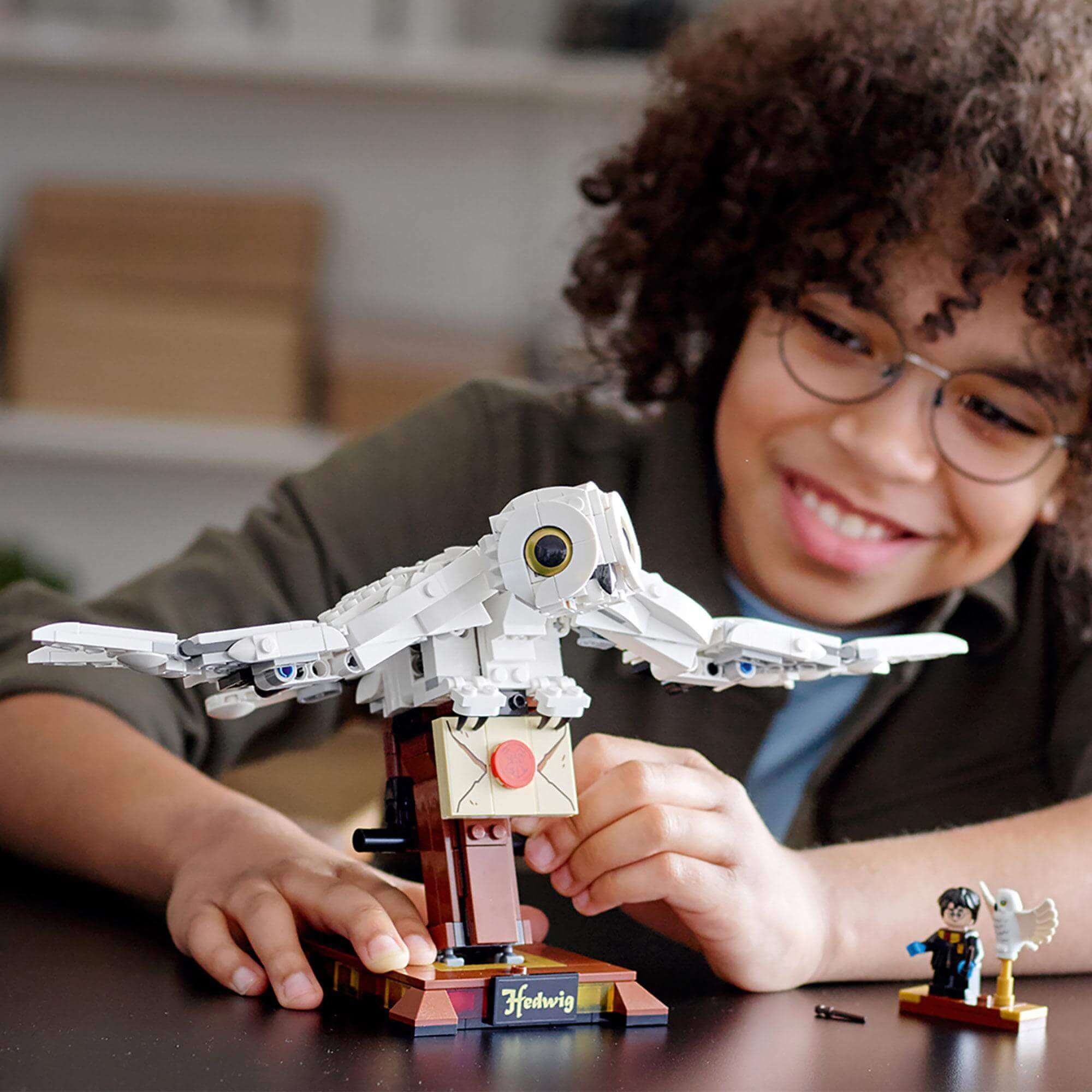 Child interacting with LEGO® Harry Potter Hedwig display model featuring 'flying' wings and a letter.