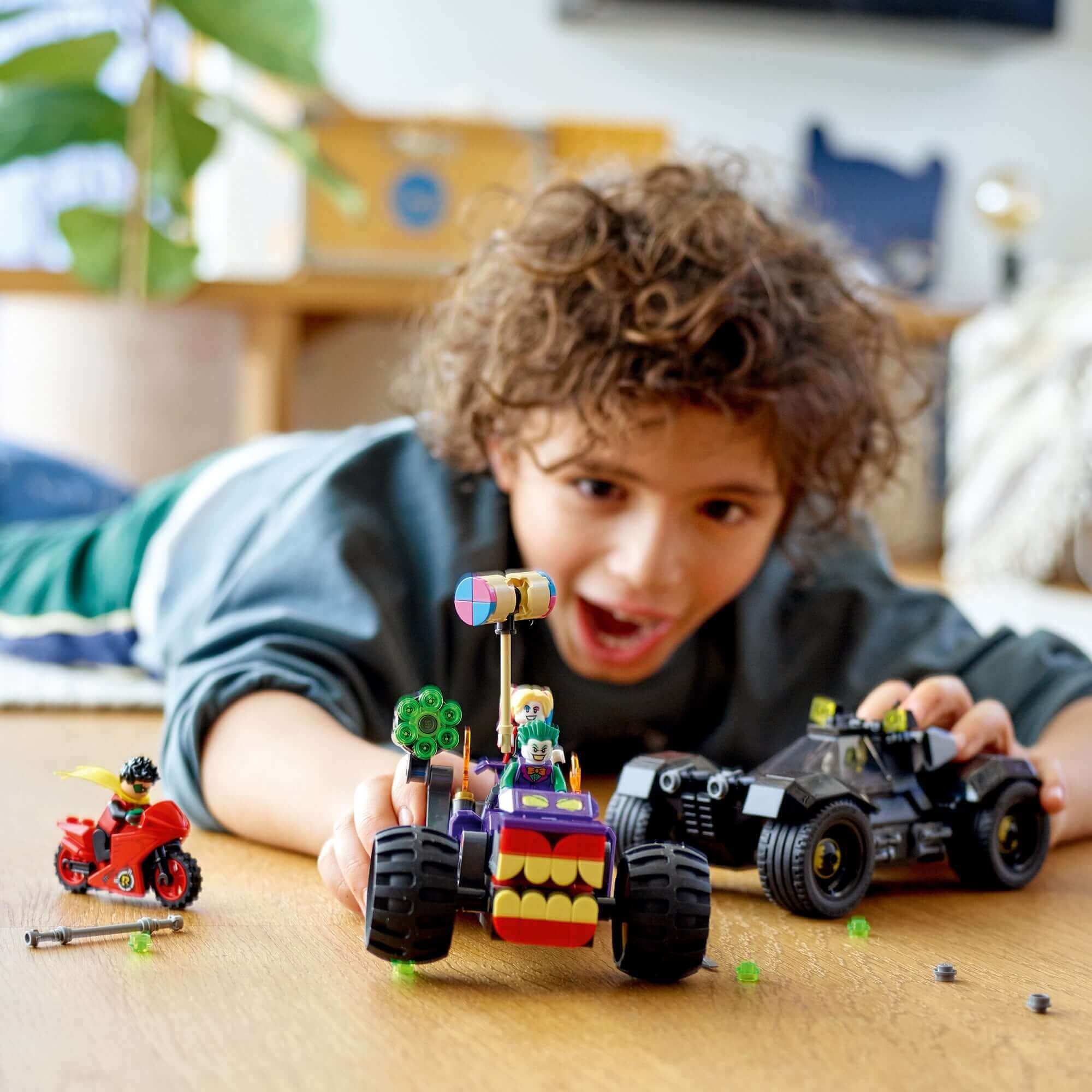 Child playing with LEGO® DC Batman Joker's Trike Chase toy set featuring Batman and Joker's vehicles.