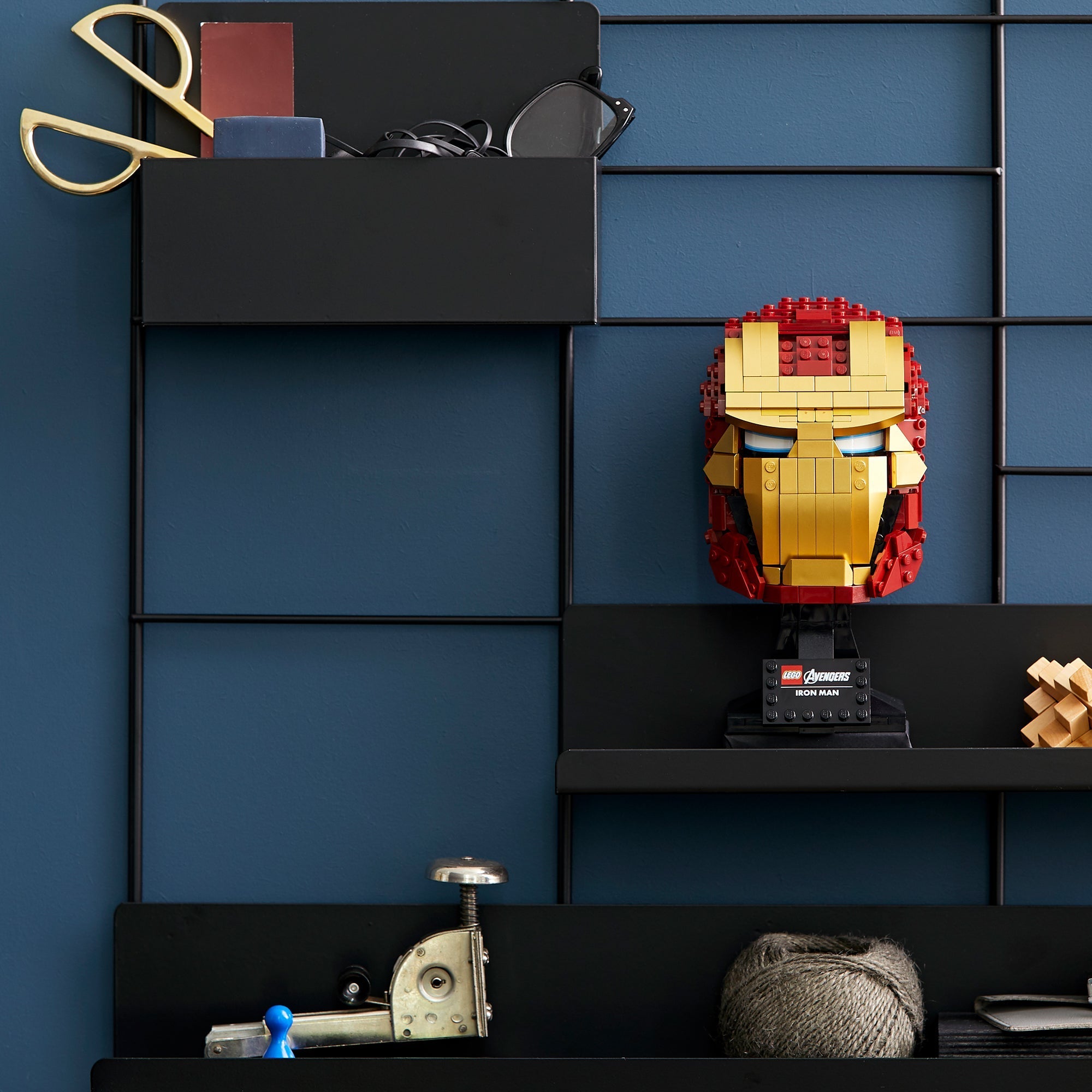 LEGO® Marvel Iron Man Helmet 76165 displayed on a black shelf against a blue wall, perfect for adult fans.