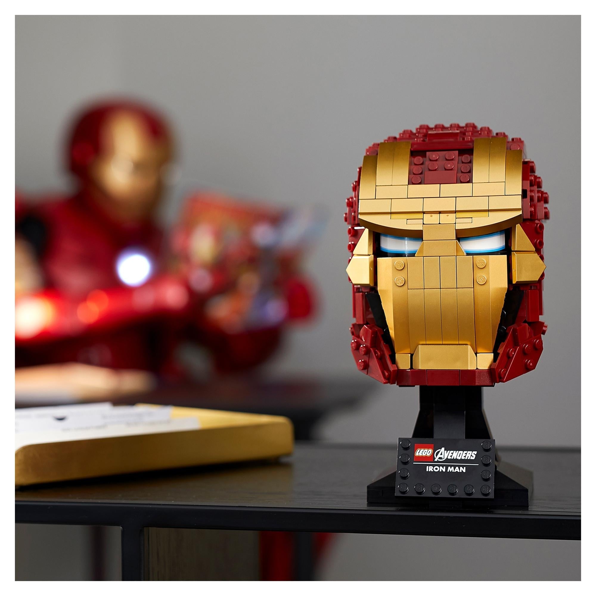LEGO Marvel Iron Man Helmet 76165 model displayed on a table with Iron Man figure in the background.