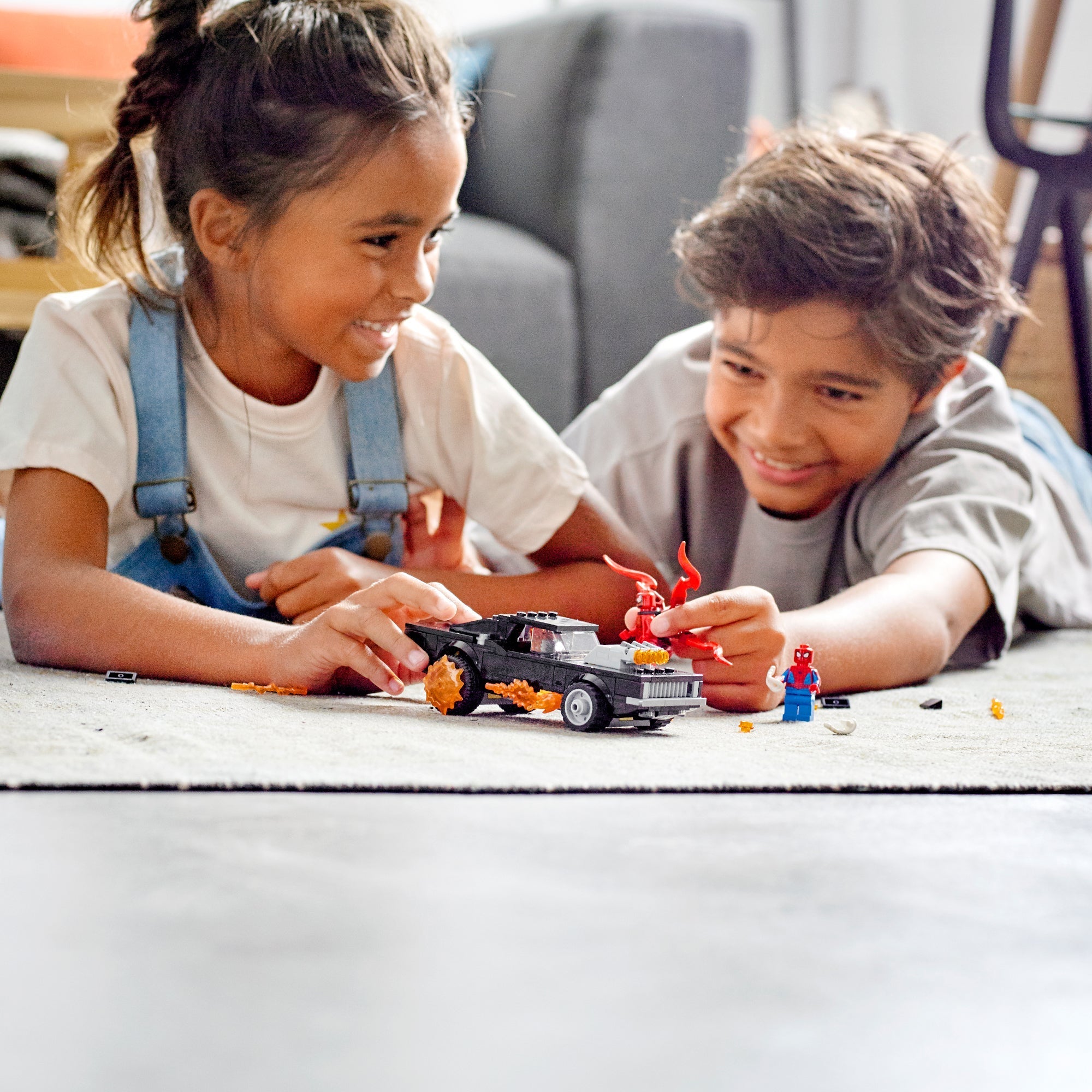 Kids playing with LEGO® Marvel Spider-Man, Ghost Rider, and Carnage toy set on a carpet, enjoying imaginative play.
