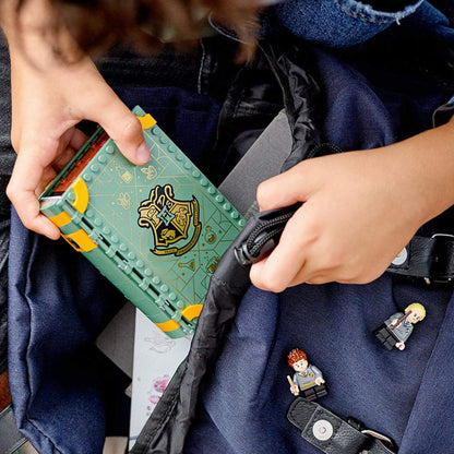 Child's hands holding LEGO Harry Potter Potions Class set with mini figures in a backpack.
