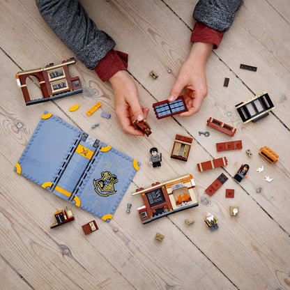 Hands assembling the LEGO® Harry Potter Hogwarts Charms Class Set 76385 with magical elements and accessories.
