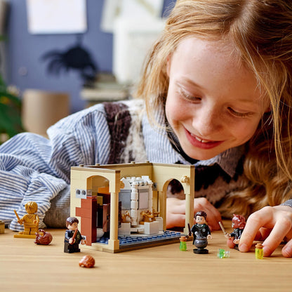 Child playing with LEGO Harry Potter 76386 set, featuring Hogwarts bathroom and character figures.