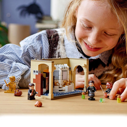 Child playing with LEGO Harry Potter Hogwarts Potion Mistake Set 76386, featuring characters and a detailed bathroom build.