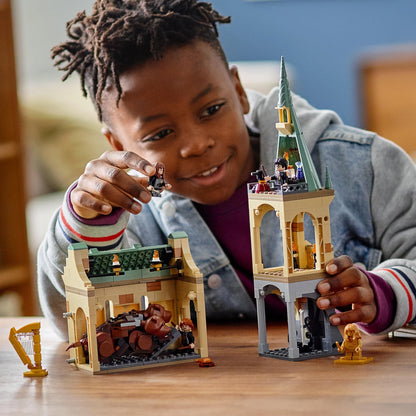 Child playing with LEGO® Harry Potter Hogwarts set, featuring Fluffy Encounter and mini-figures of Harry, Ron, and Hermione.