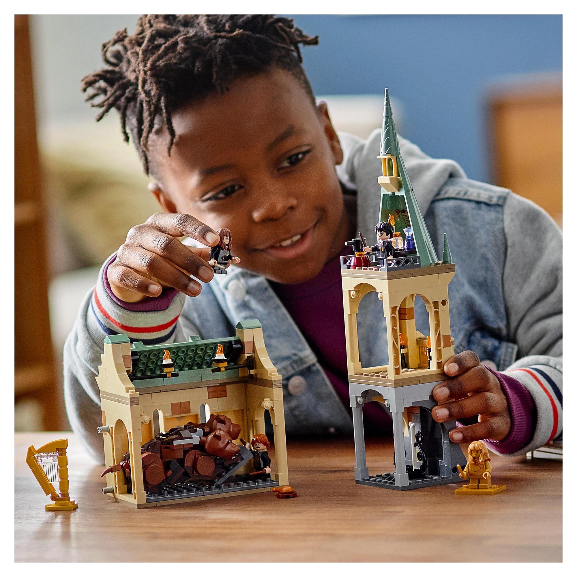 Child playing with LEGO® Harry Potter Hogwarts playset, featuring Fluffy and iconic Hogwarts details.
