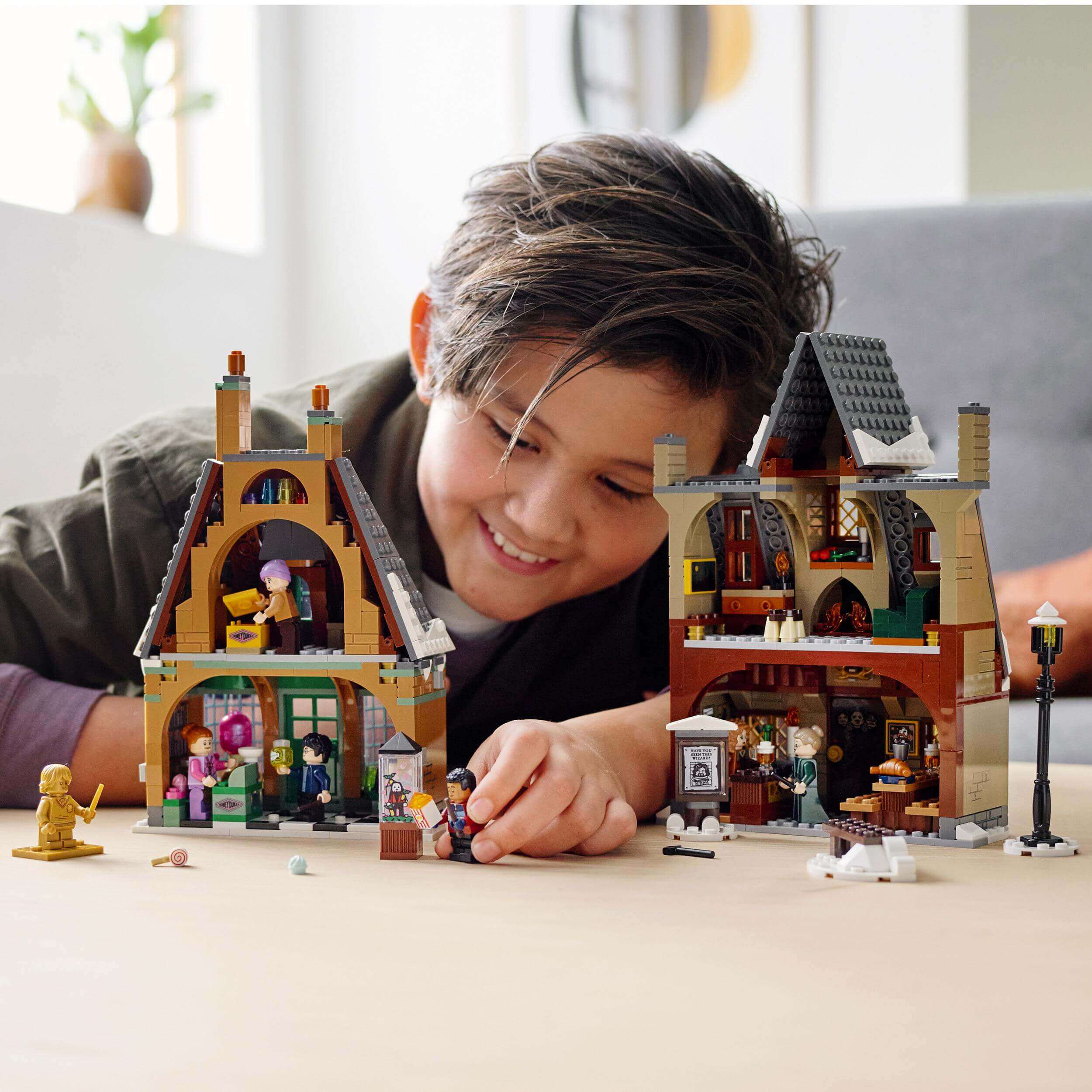 Child enjoying the LEGO® Harry Potter Hogsmeade Village Visit Set 76388, playing with detailed miniature buildings.