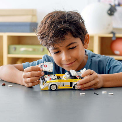 Boy building and displaying a LEGO® Speed Champions Audi Sport Quattro S1 model car with accessories.