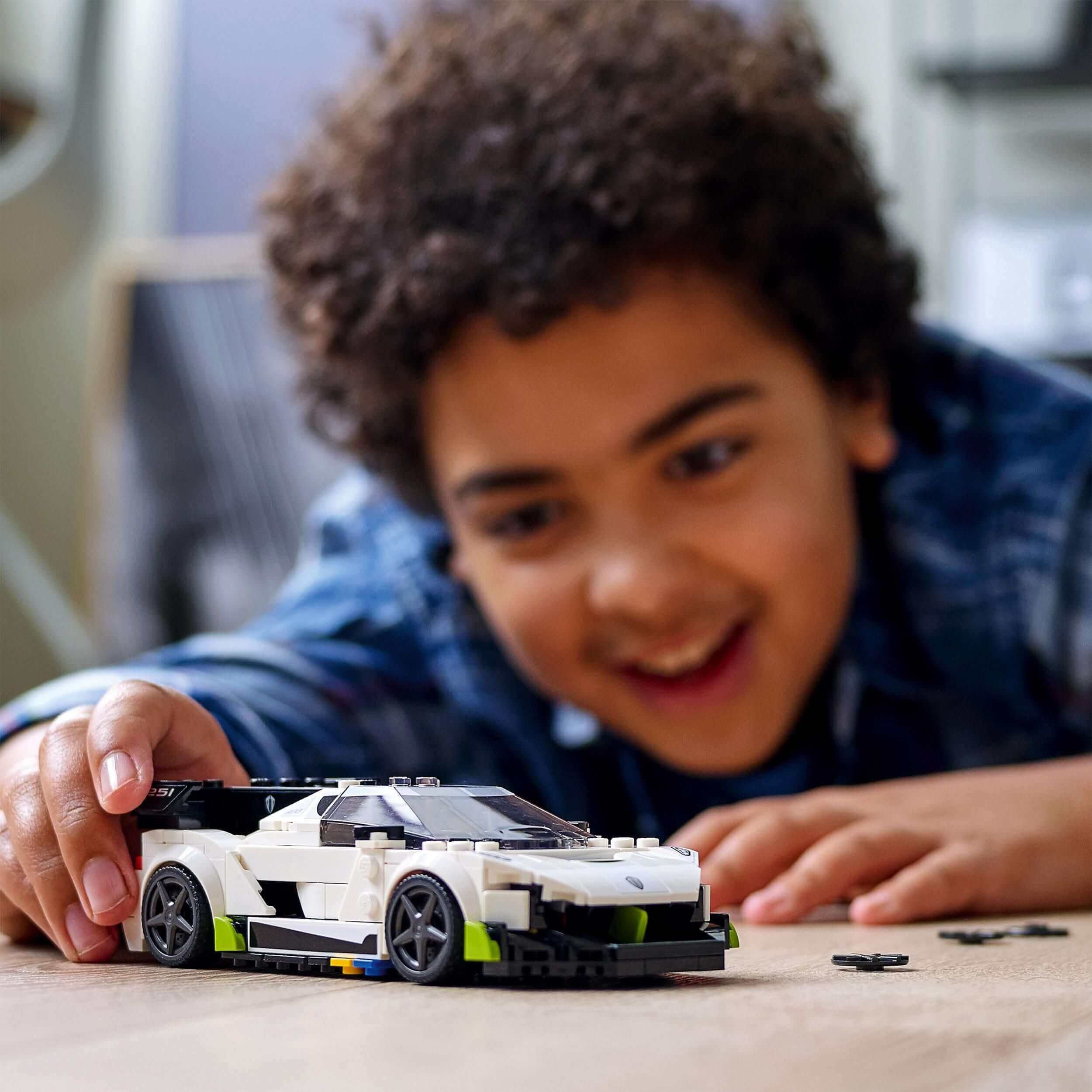 Child enjoying LEGO® Speed Champions Koenigsegg Jesko car toy 76900, building and playing with the hypercar replica.