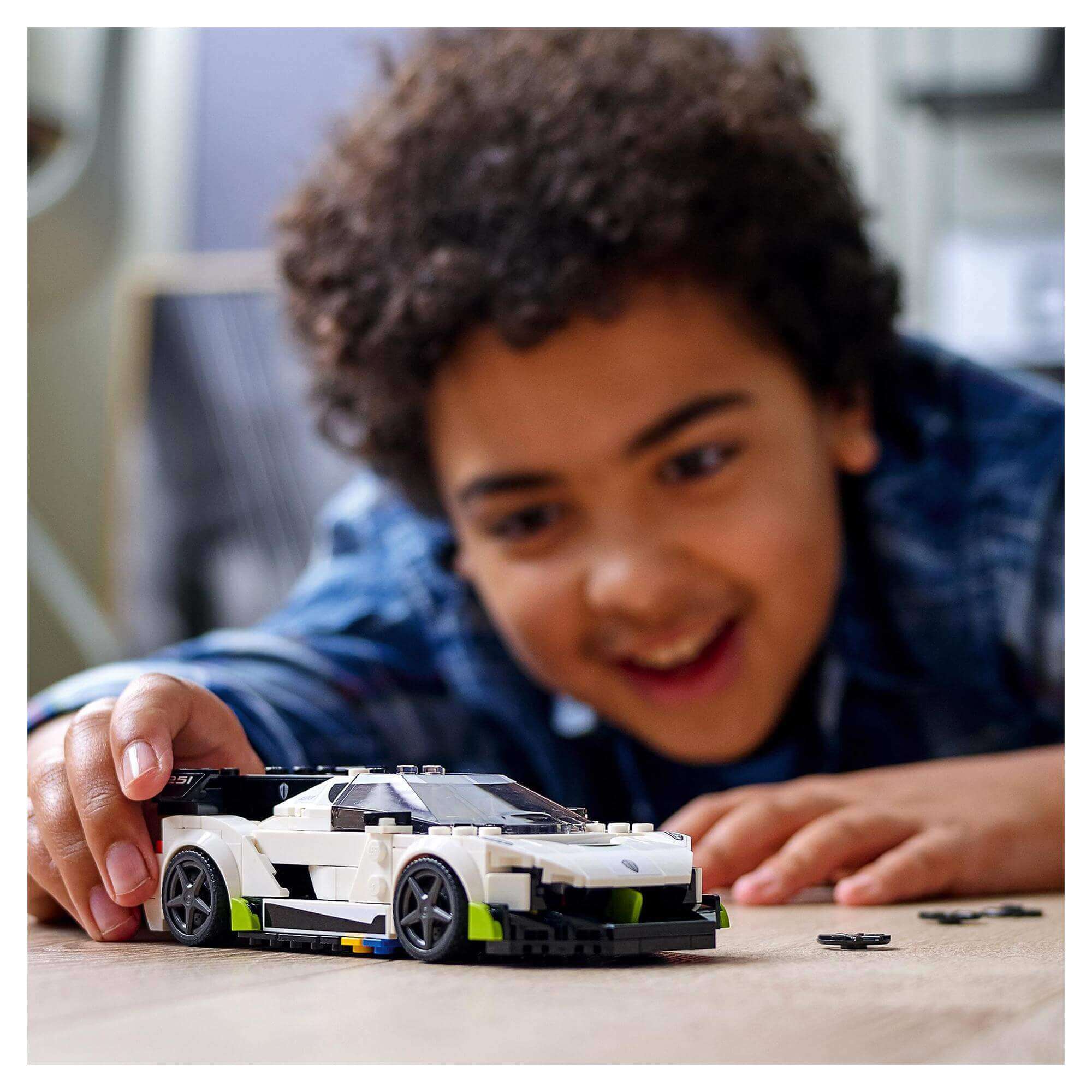 Child playing with LEGO® Speed Champions Koenigsegg Jesko car toy, enjoying imaginative racing fun.