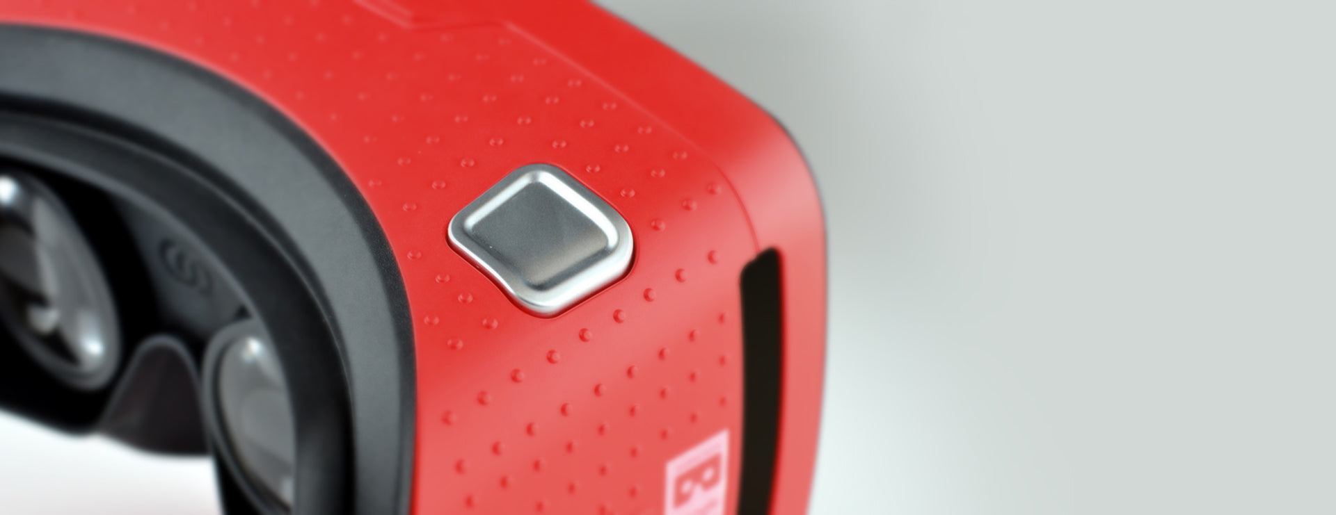 Close-up of a red VR viewer with a textured grip and control button, part of the RedboxVR Classroom VR/AR kit.