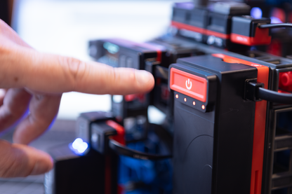 Close-up of a hand pressing the power button on a robotics kit from the Sphero Blueprint Engineering Class Pack.
