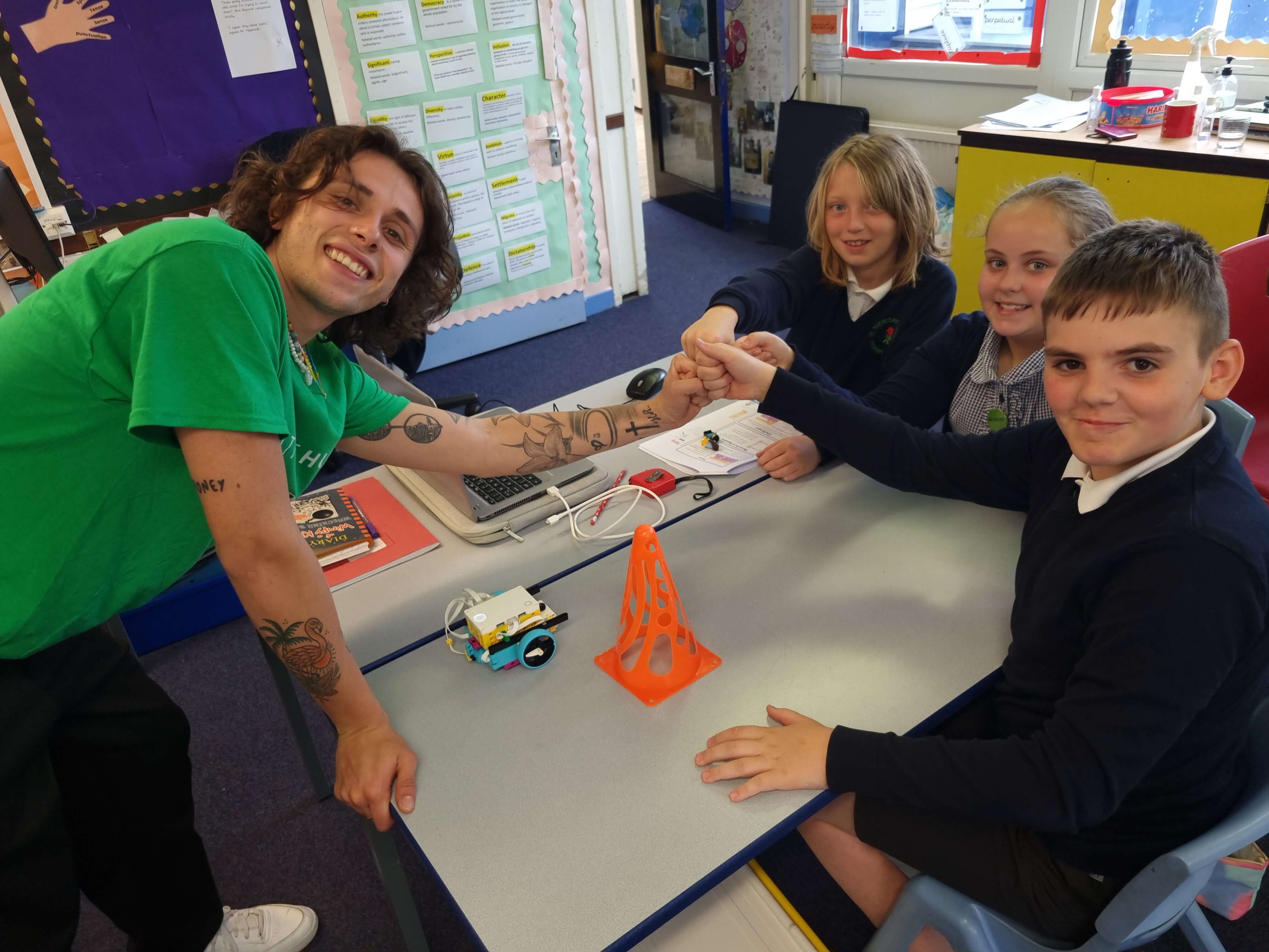 Instructor helping students with robotics project in classroom, showcasing teamwork and learning.