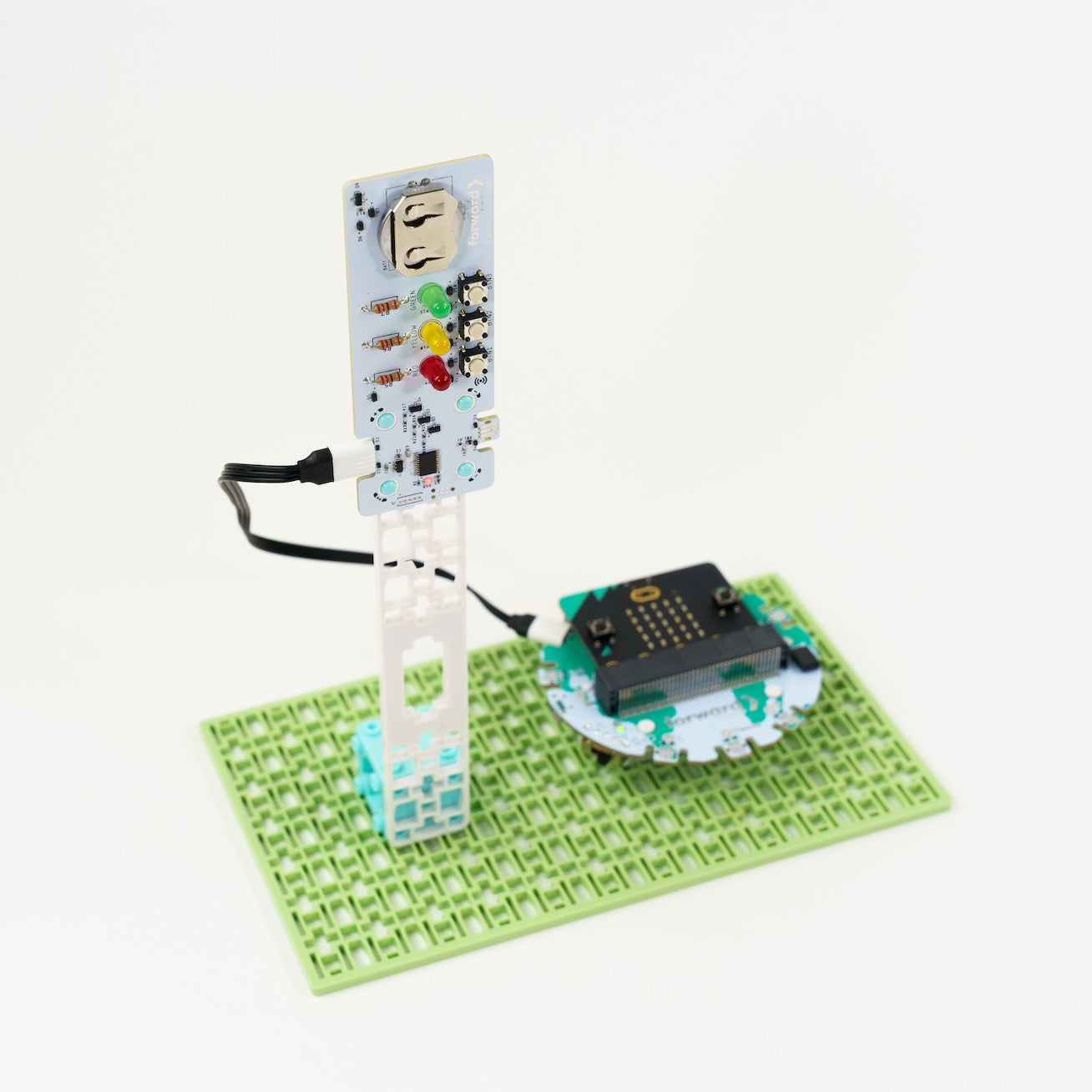 A completed Smart Soldering Kit featuring a vertical "Traffic Light" circuit board with green, yellow, and red LEDs. The board is mounted on a white modular frame and connected via cable to a micro:bit interface on a green baseplate.