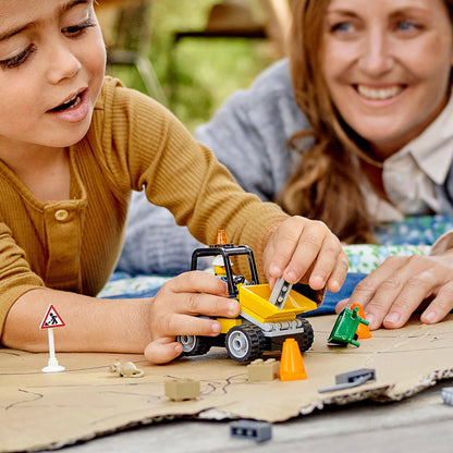 Child playing with LEGO® City Roadwork Truck and construction accessories, engaging in creative roadworks activity.